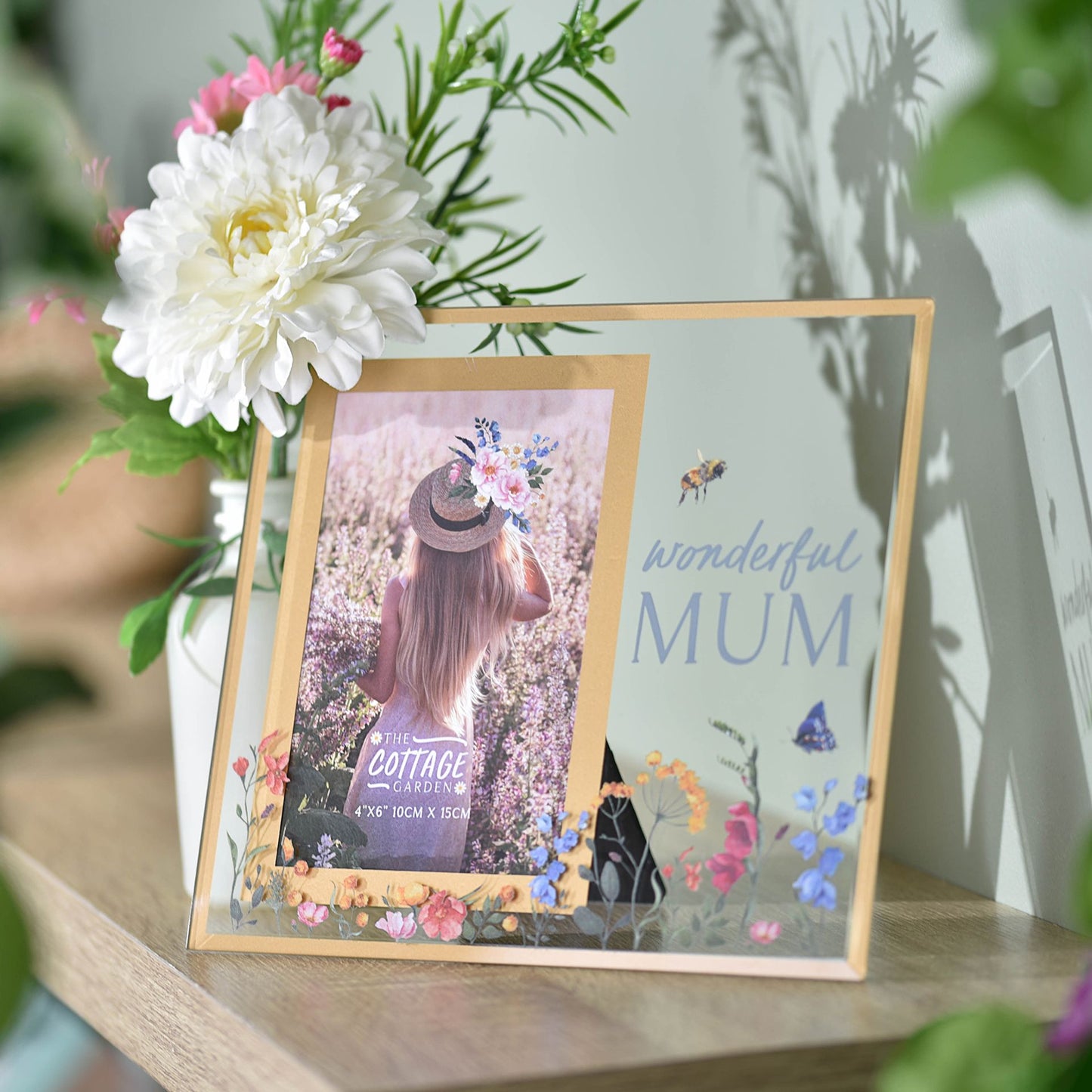 Decorative photo frame with floral design on a surface with flowers in the background