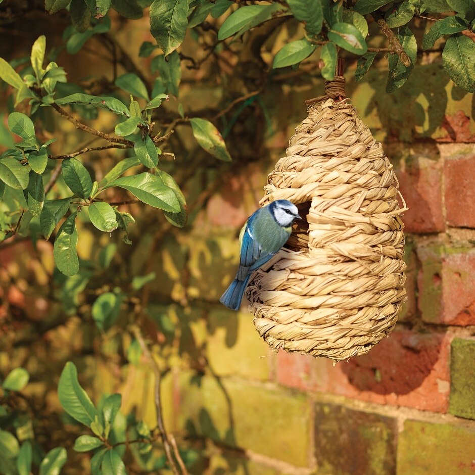 Peckish Bird Roosting Pouch hanging in a tree with a small bird on the side