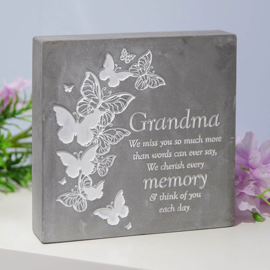 Decorative stone plaque with engraved text and butterflies on a light background