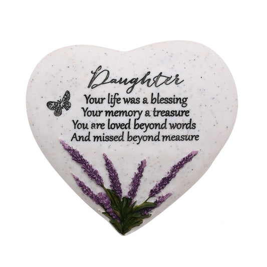 Heart-shaped stone with engraved text and pressed flowers on a white background