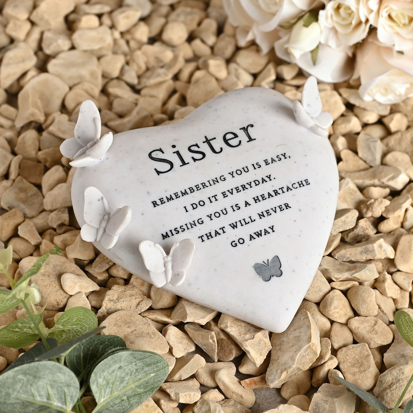 Heart-shaped stone with 'Sister' message on pebbles with flowers