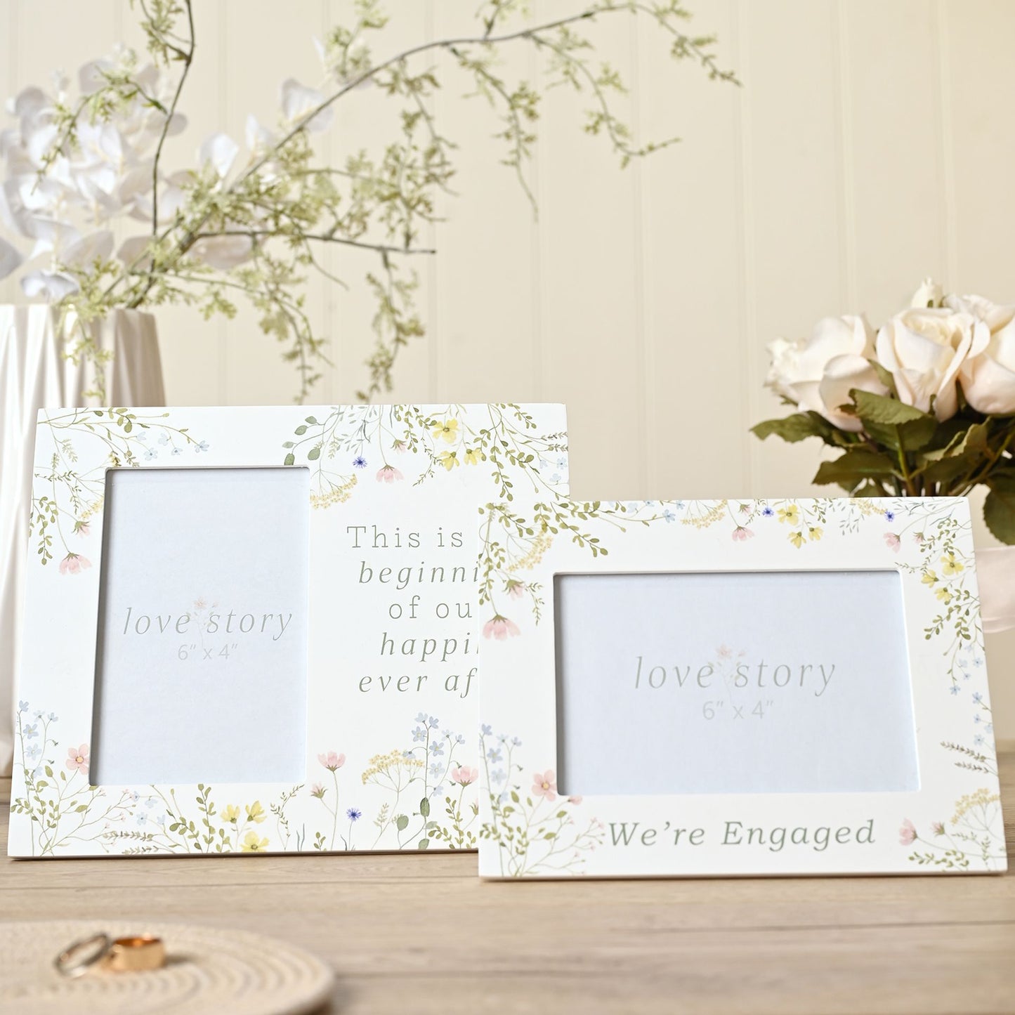 Two decorative photo frames with floral designs and romantic text on a wooden surface.