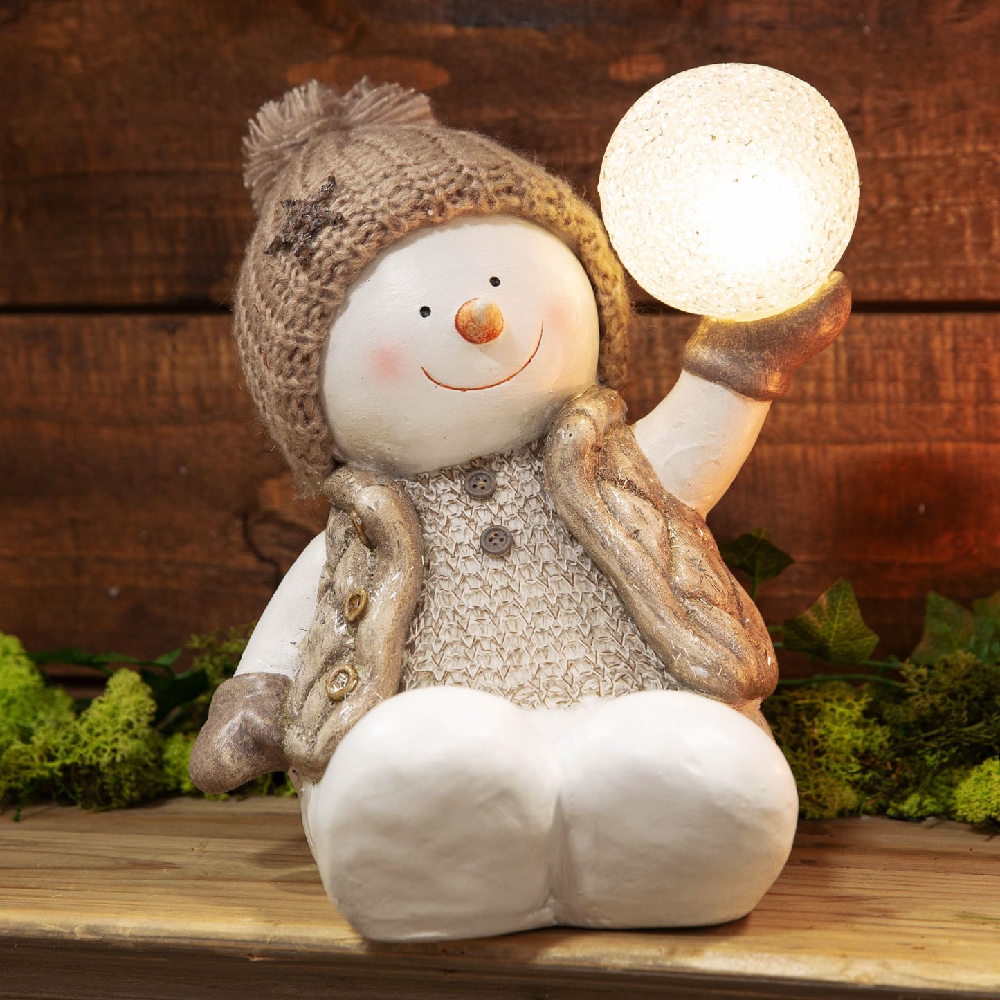 Decorative snowman figurine holding a light bulb against a wooden background