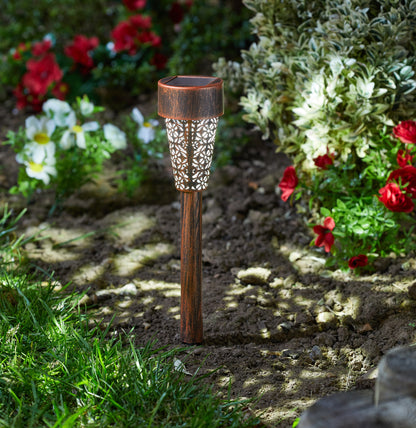 Decorative garden light in a garden setting with flowers and grass.