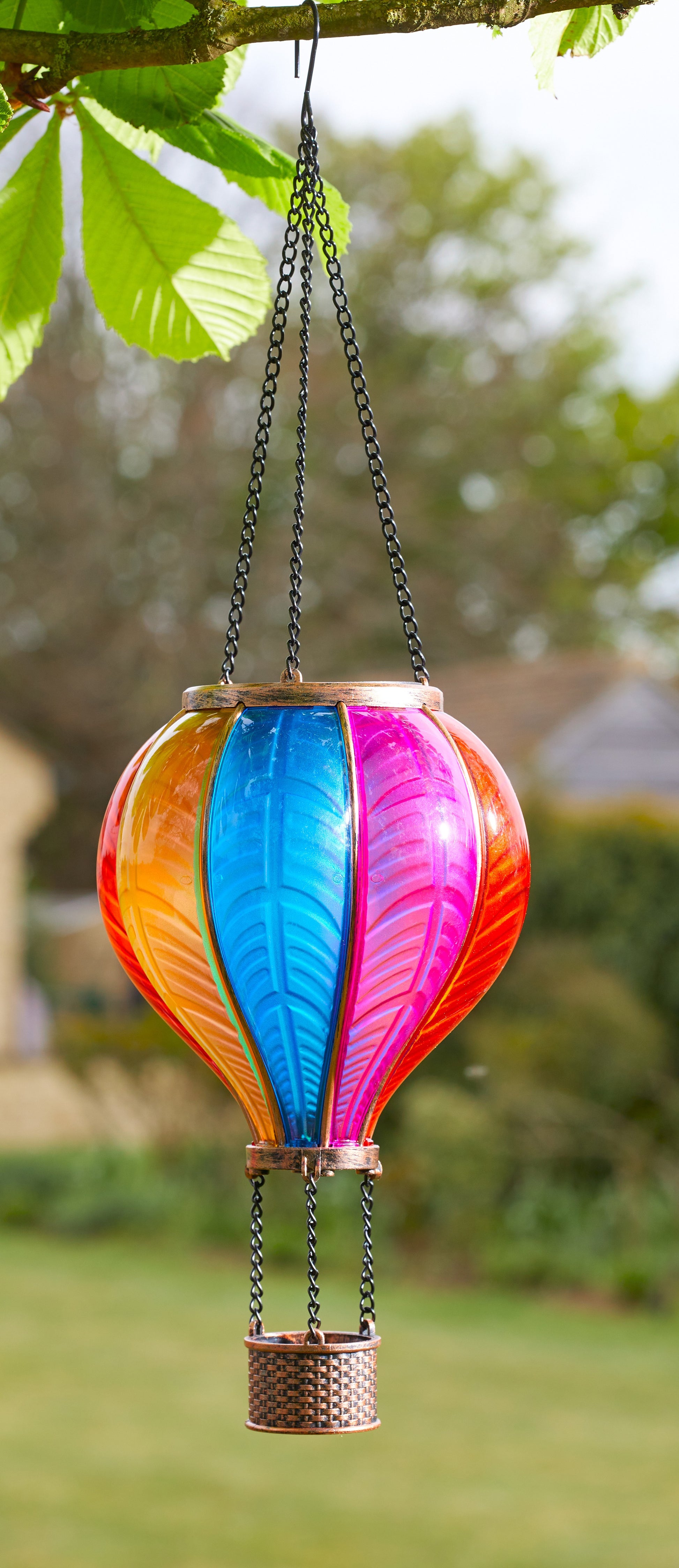 Colorful hot air balloon-shaped hanging decoration in a garden setting