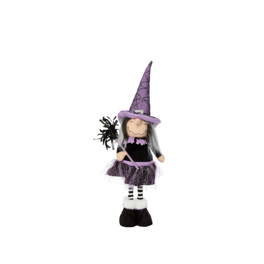 A decorative witch doll with a purple pointed hat, black dress, grey hair, striped socks, and black shoes, holding a small black spider on a white background.