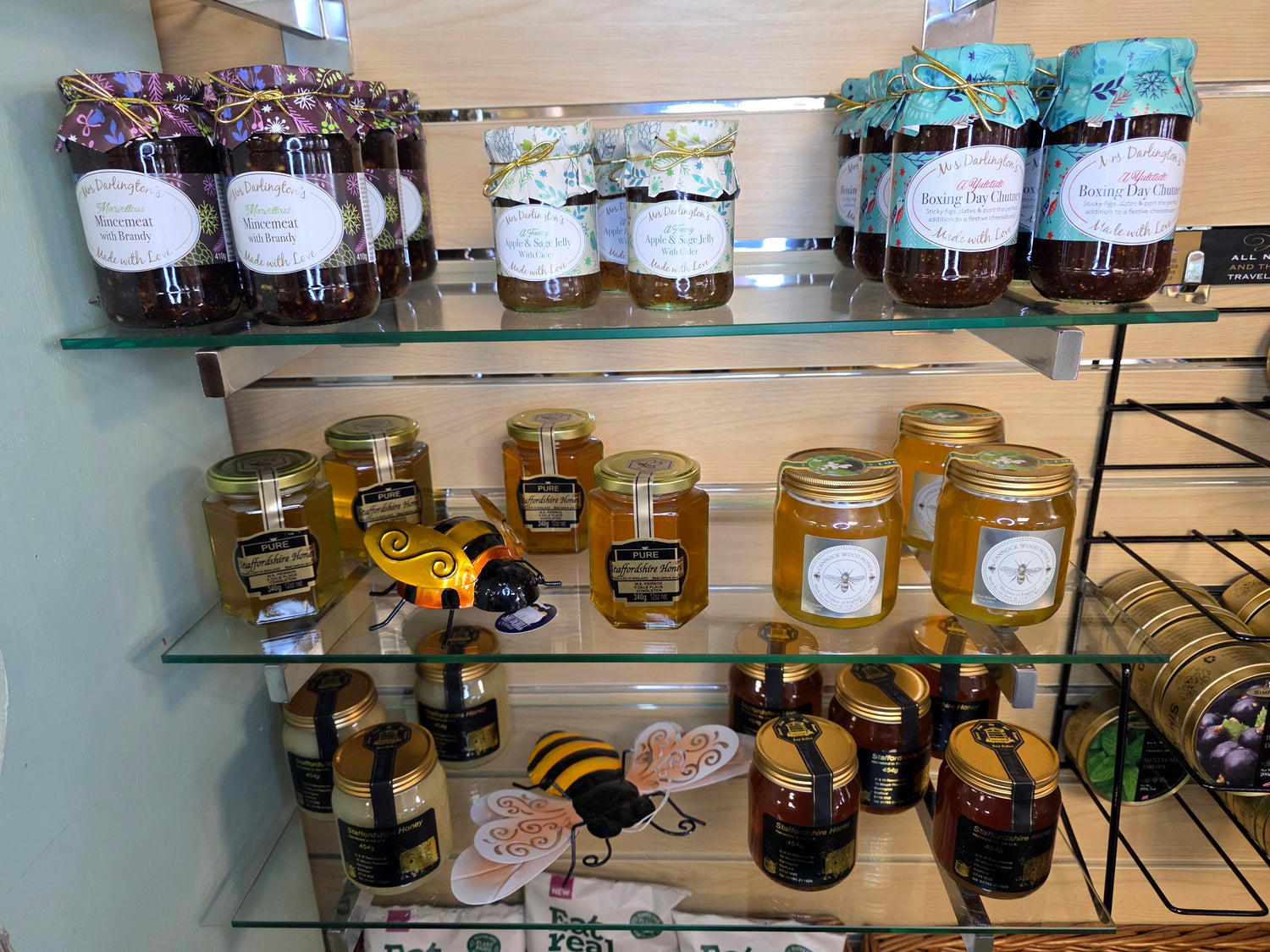 Shelf displaying various jars of honey and jam with decorative labels.