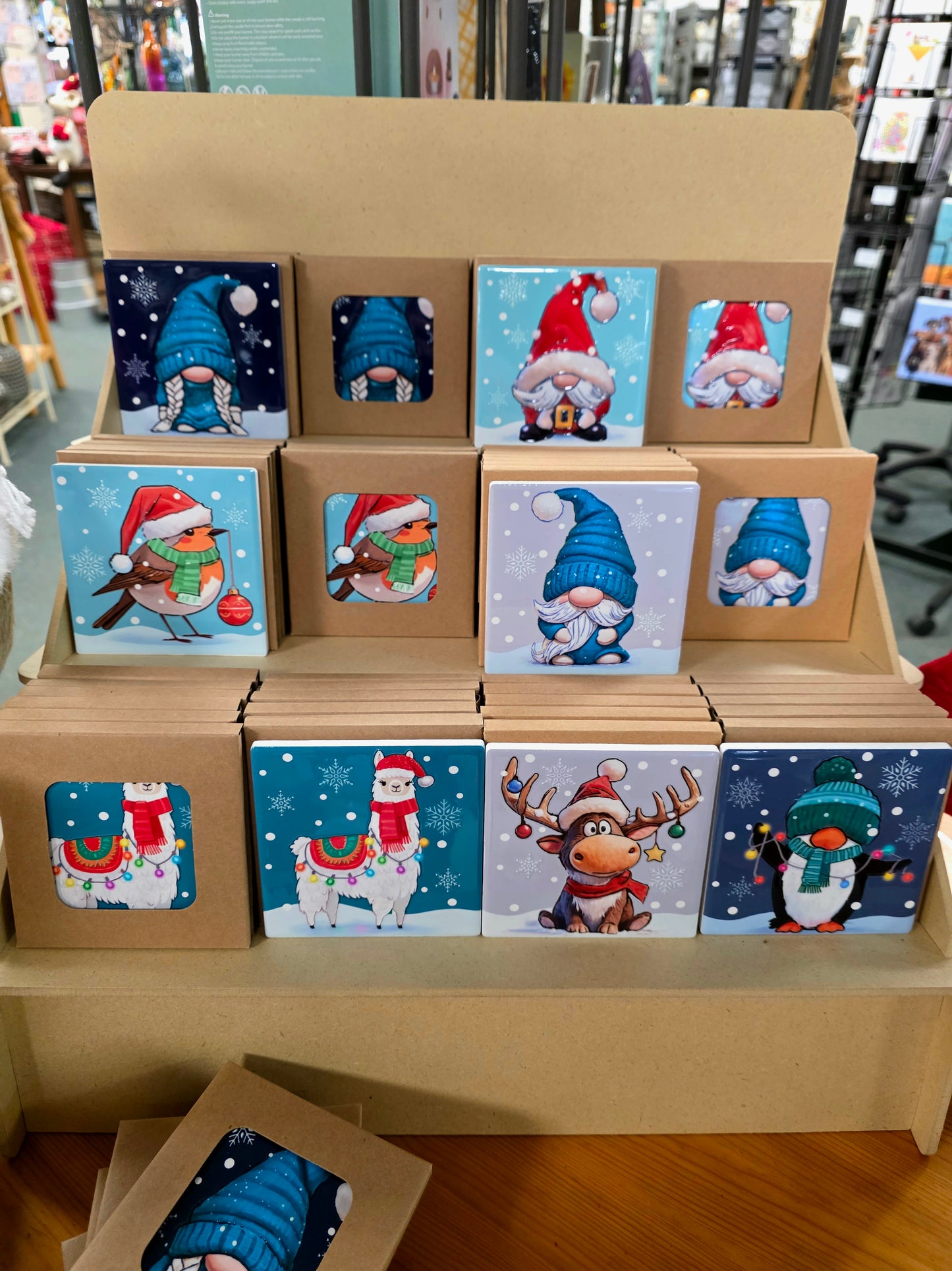 Set of small boxes with Christmas-themed illustrations on a cardboard stand.
