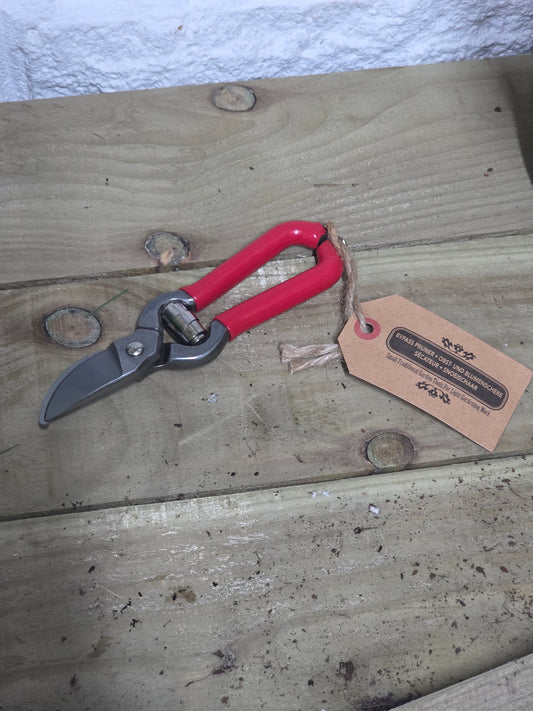 Red bypass pruners on a wooden table