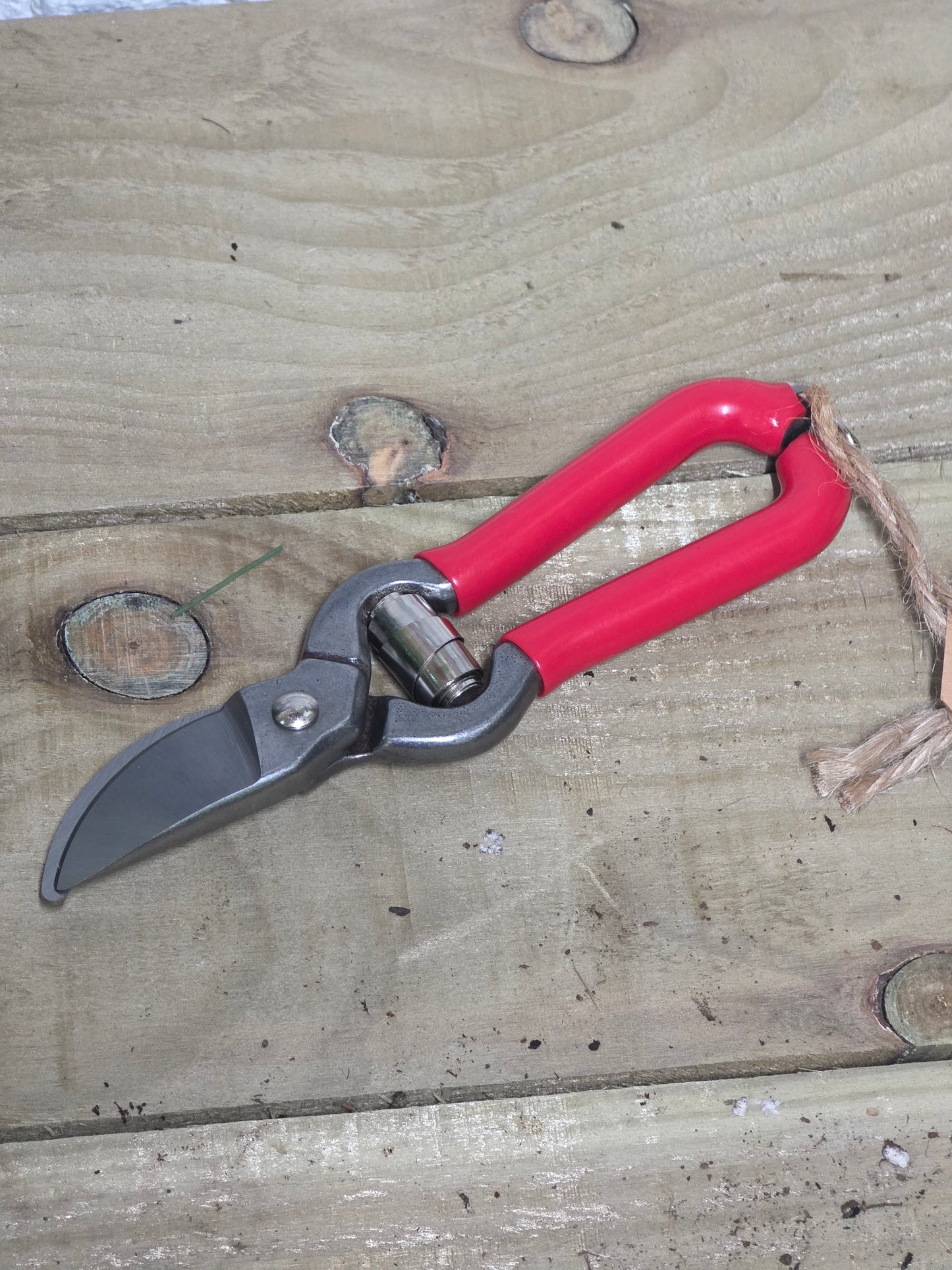 Red bypass pruners on a wooden table