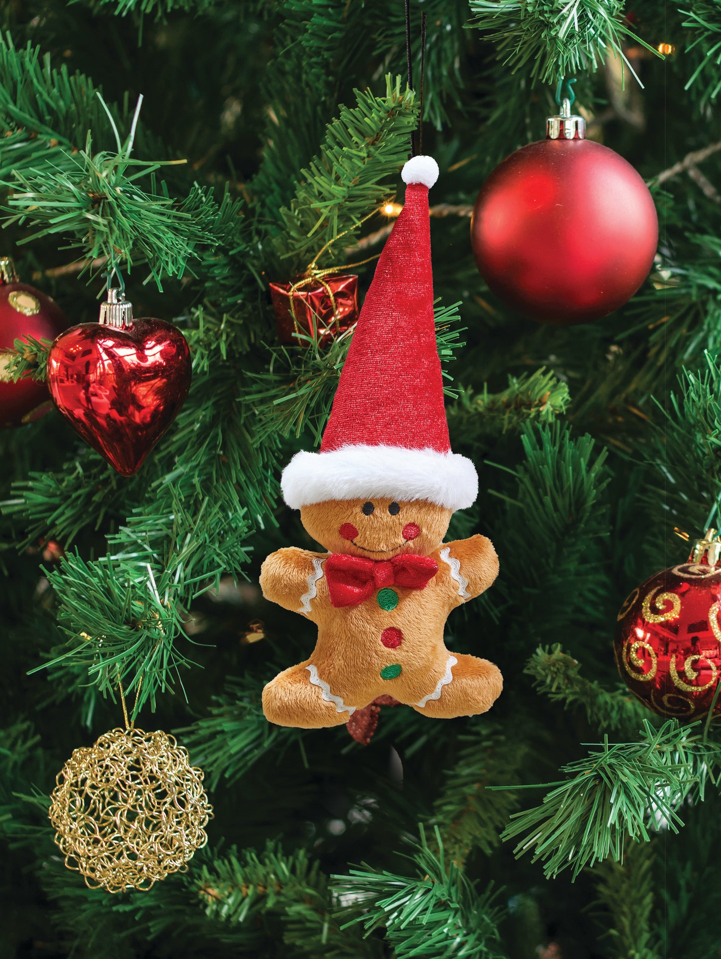 Gingerbread man ornament with a red hat on a Christmas tree with colorful ornaments.