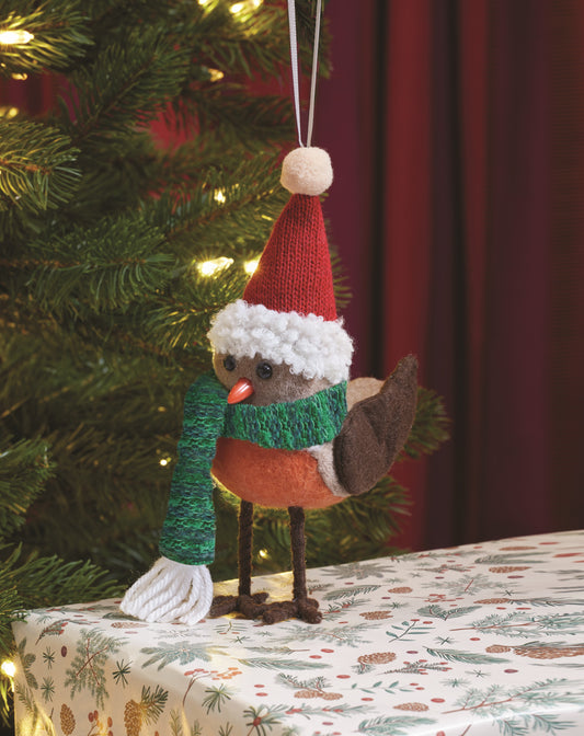 Knitted robin decoration wearing a Santa hat and scarf, hanging on a Christmas tree.