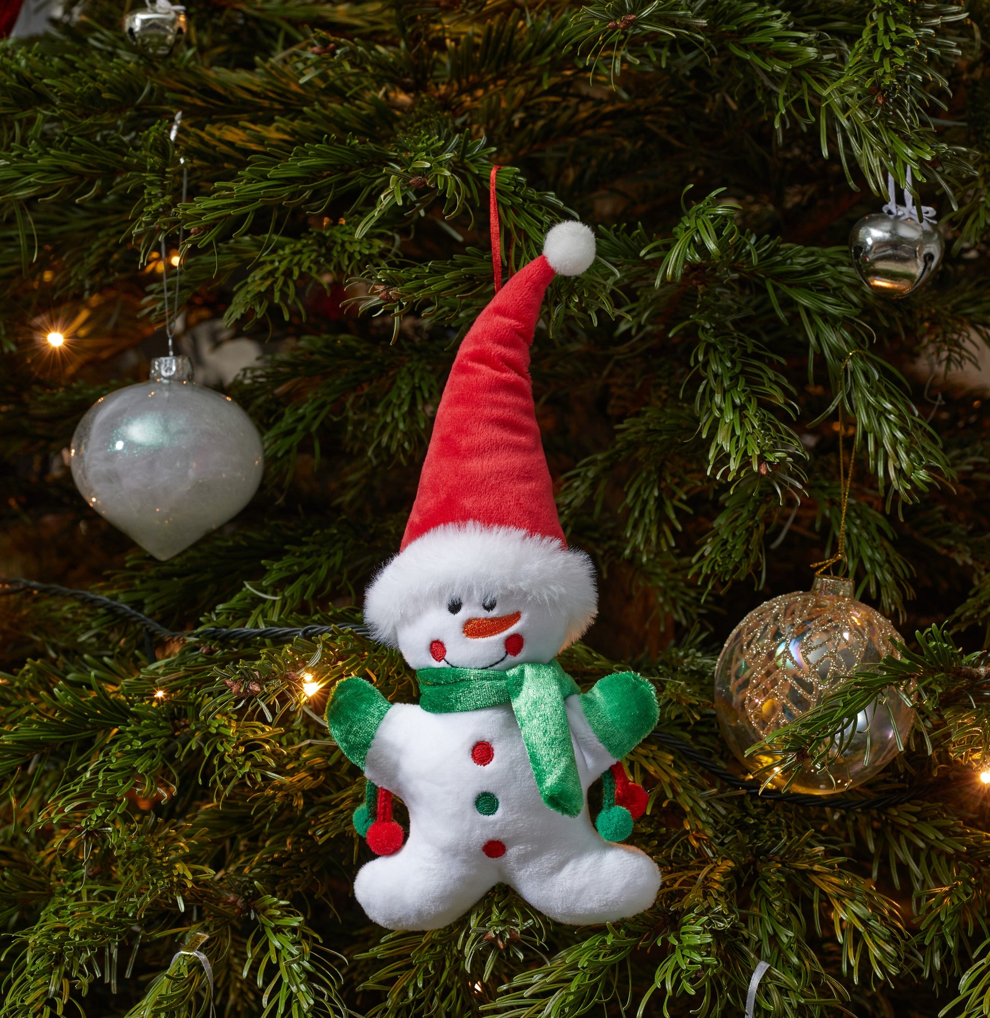 Snowman ornament on a decorated Christmas tree with lights and ornaments.