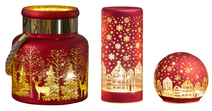 Set of three red candle holders with gold winter scene designs on a white background