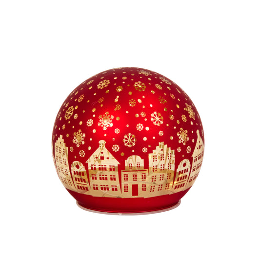 Decorative red ball with gold snowflakes and house silhouettes on a white background