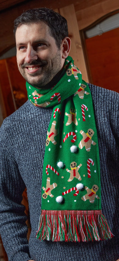 Man wearing a festive green scarf with gingerbread men and candy cane patterns.