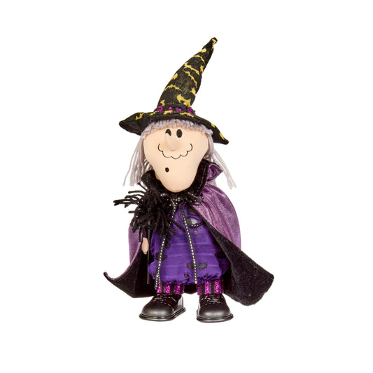 Toy figure of a witch wearing a purple outfit and black hat on a white background
