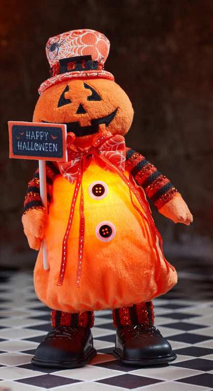 Halloween-themed plush pumpkin with a sign saying 'Happy Halloween' on a checkered floor.