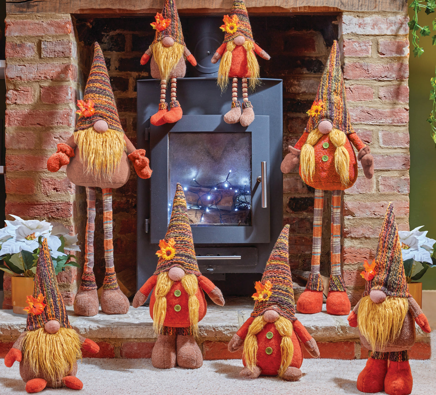 Decorative gnomes in front of a fireplace with a lit fire.