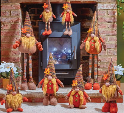 Decorative gnomes in front of a fireplace with a screen displaying a snowy landscape.