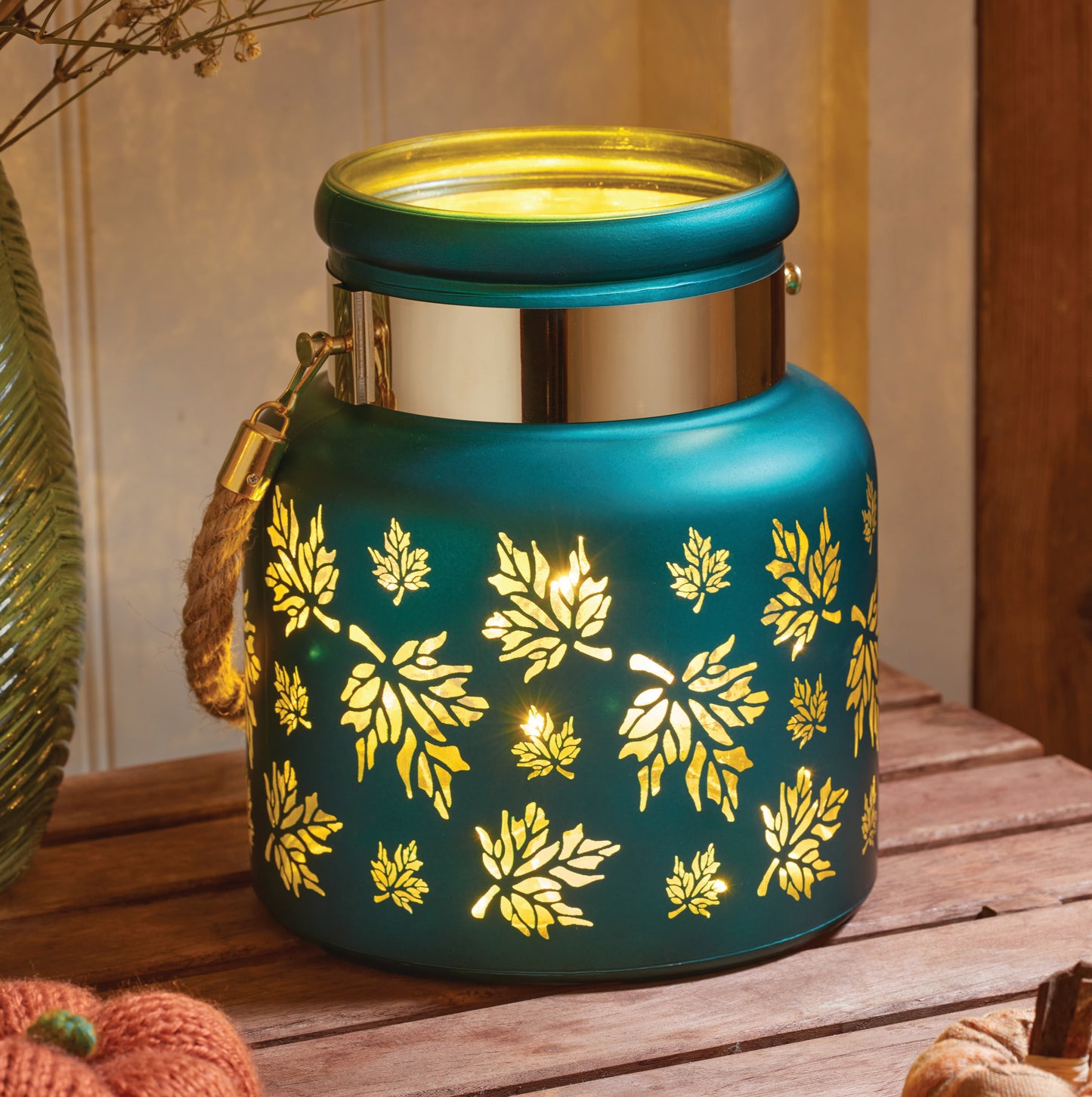 Decorative teal lantern with gold leaf pattern on a wooden surface
