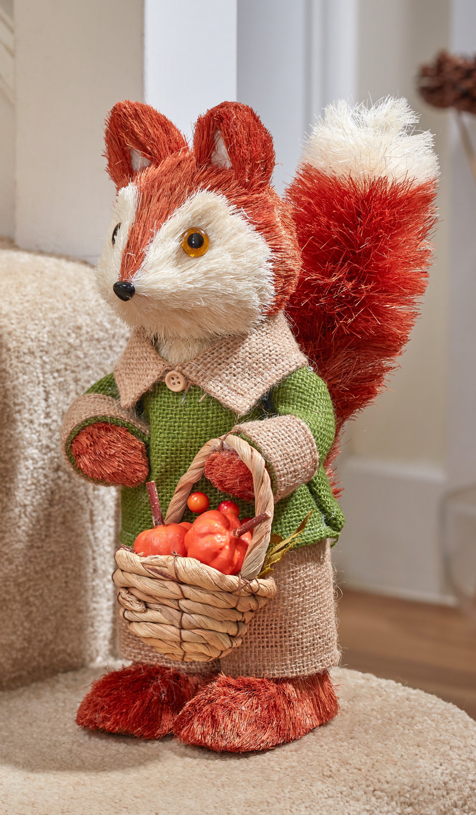 Knitted fox toy holding a basket of apples in a home setting