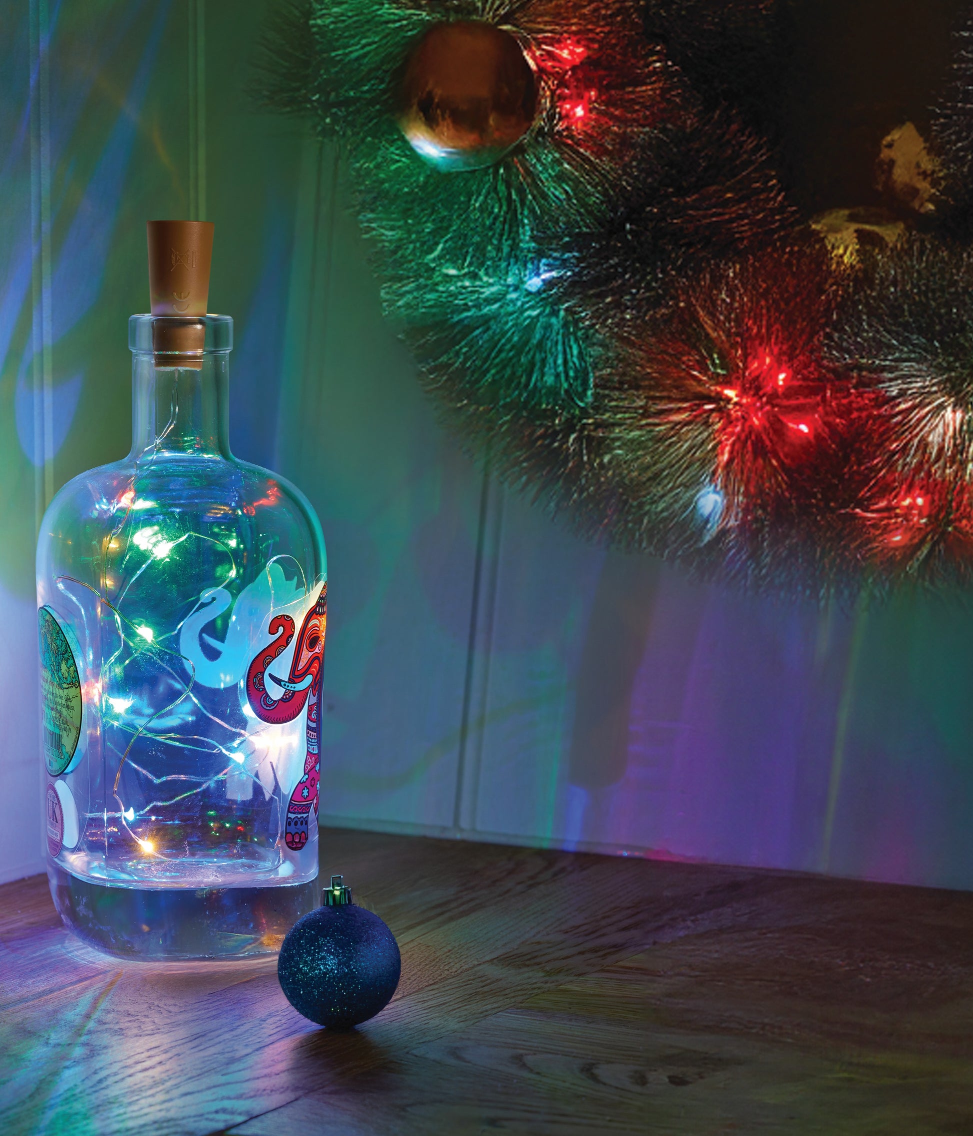 Decorative bottle with string lights next to a Christmas wreath
