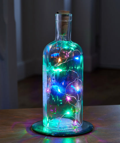Decorative glass bottle with colorful lights against a dark background