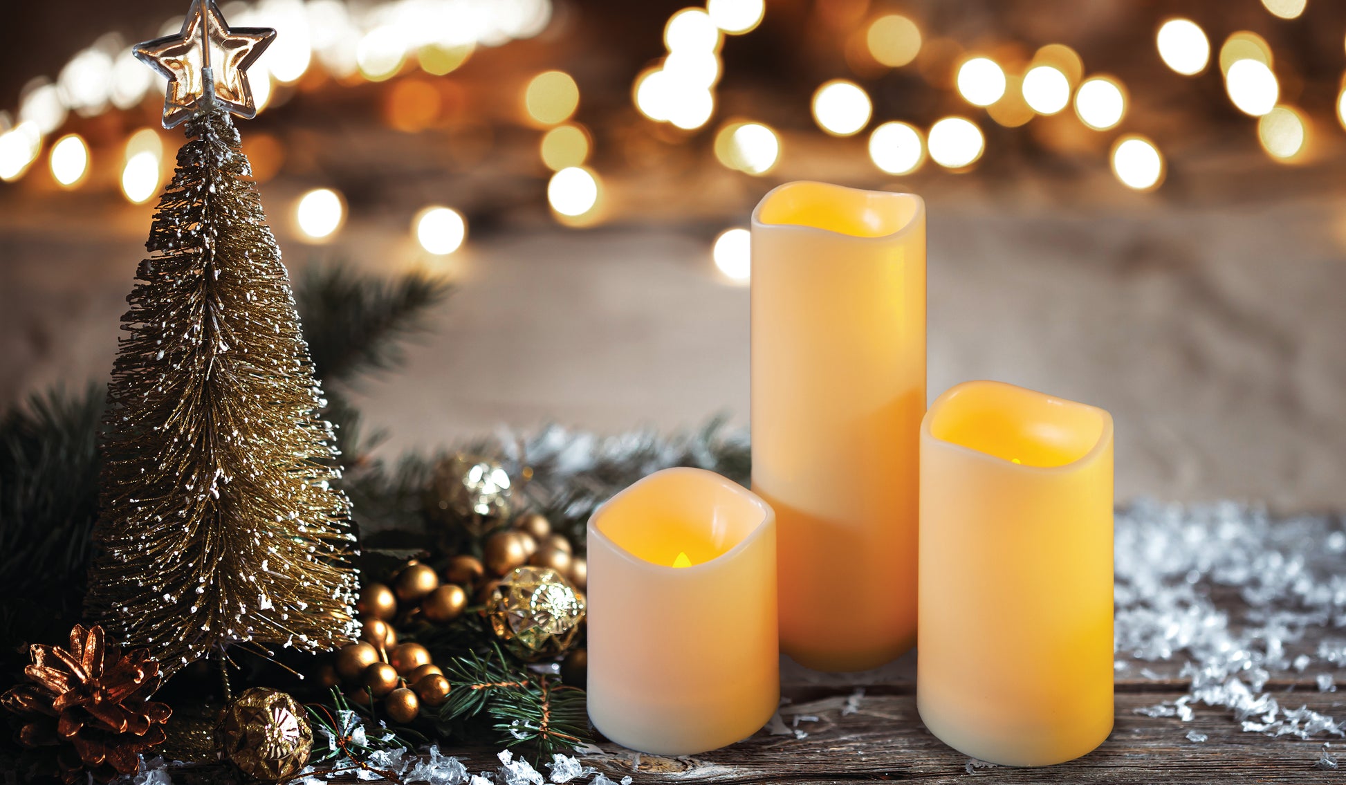 Decorative candles and a small Christmas tree with a blurred festive background