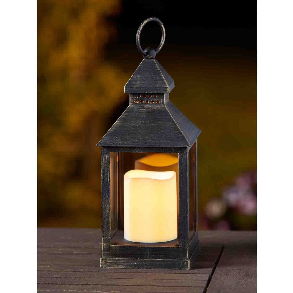 Decorative lantern with a lit candle inside on a wooden surface.
