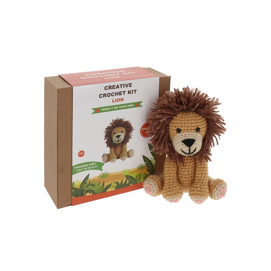Crocheted lion toy next to its packaging on a white background