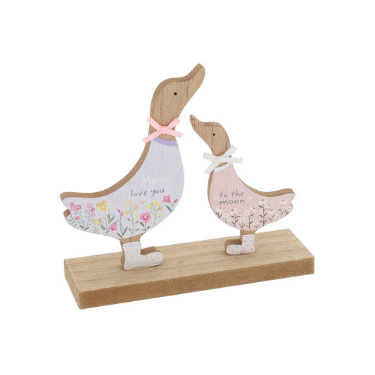 Decorative wooden figurines of a mother duck and her duckling on a stand with floral patterns and text.