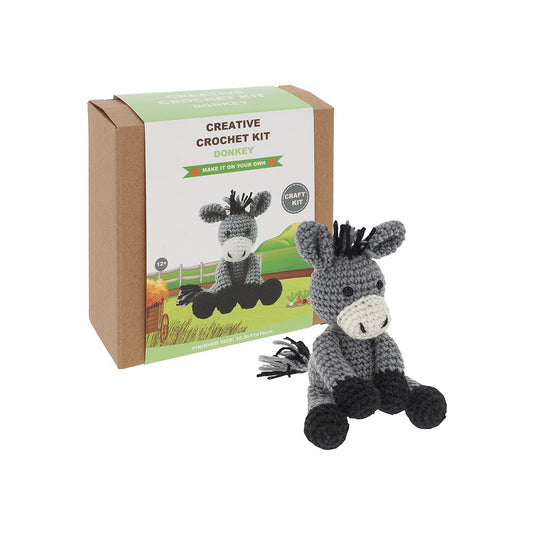 Crocheted donkey toy next to its packaging box on a white background