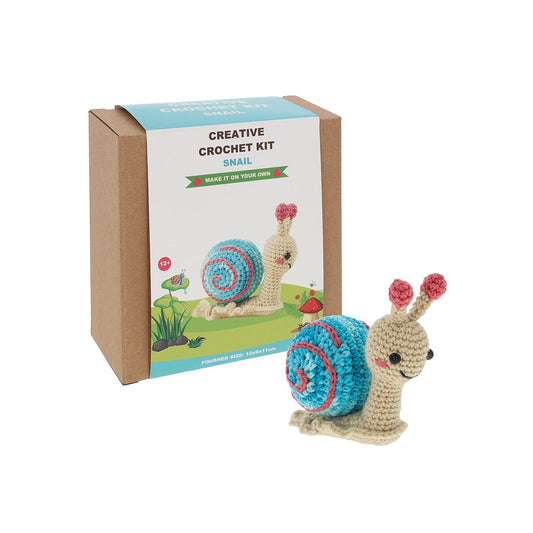 Crocheted snail toy in front of a box labeled 'Creative Crochet Kit Snail'.