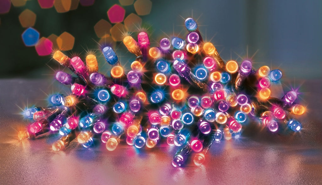 Multicolored string lights on a reflective surface with a blurred background