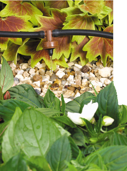 Small water pump in a garden with plants and pebbles