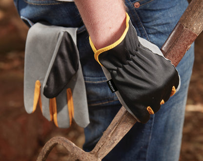 Person wearing gray gardening gloves with yellow accents holding a tool.