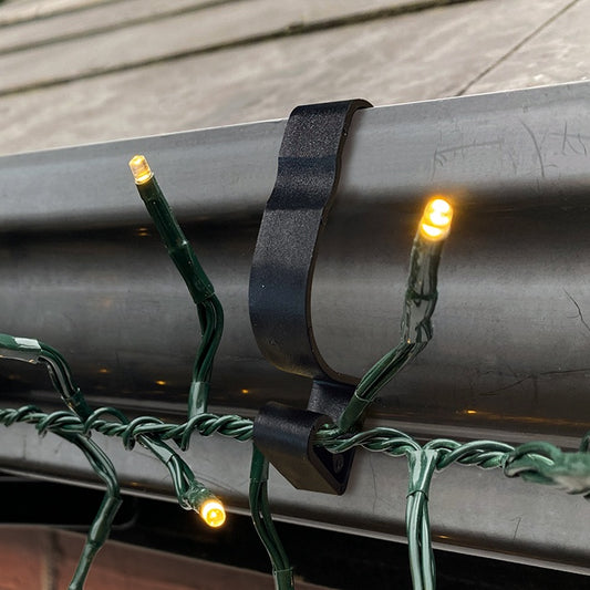 Gutter light holder with Christmas lights attached to a roof gutter