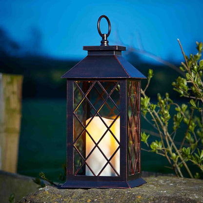 Decorative lantern with a candle inside on a stone surface at night.