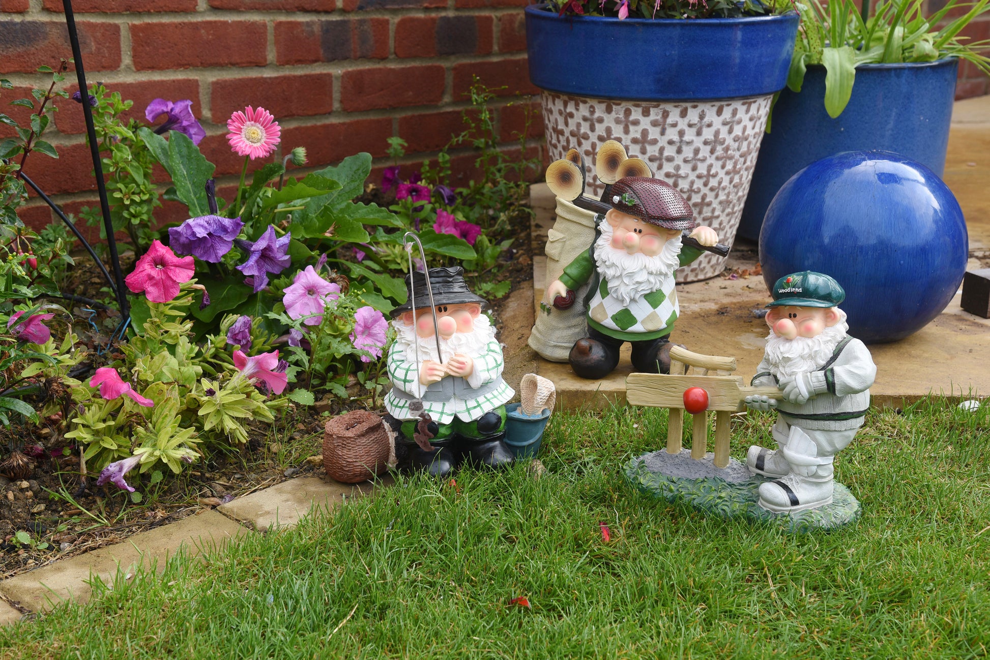 Gnome figurines in a garden setting with flowers and potted plants.