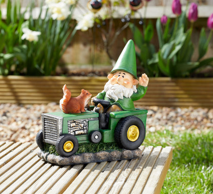 Gnome figurine driving a tractor with a squirrel on a garden setting