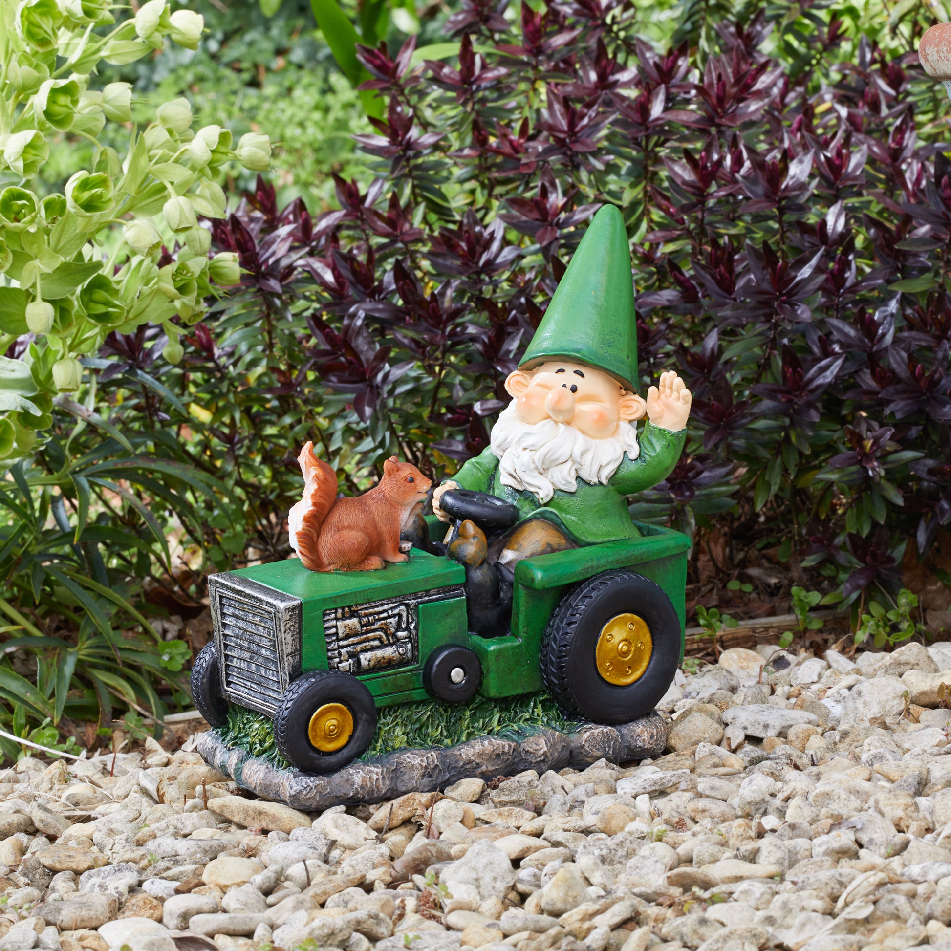 Gnome figurine driving a tractor with a squirrel on a garden setting