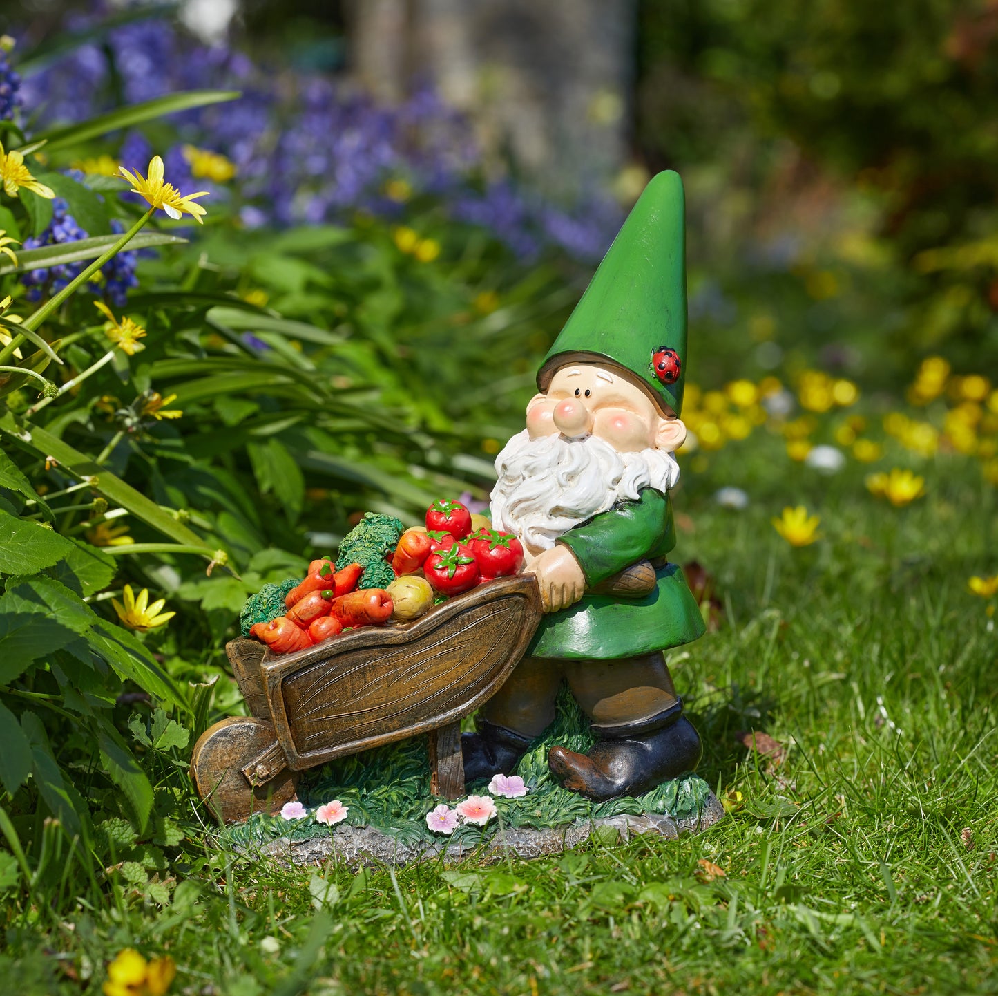 Gnome figurine with a wheelbarrow of vegetables in a garden setting