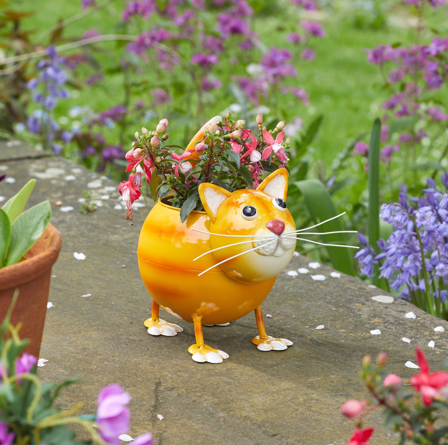 Cat-shaped flower pot with plants on a garden path