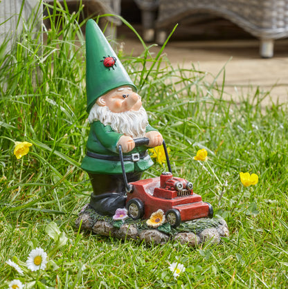 Gnome figurine with a green hat and red lawn mower on grass