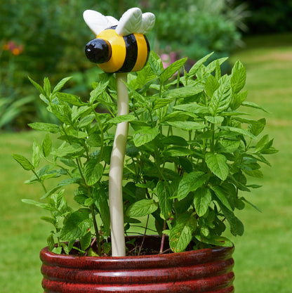 Bee-shaped garden tool in a potted plant with a blurred green background