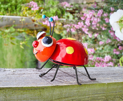 Colorful ladybug-shaped object on a wooden surface with flowers in the background