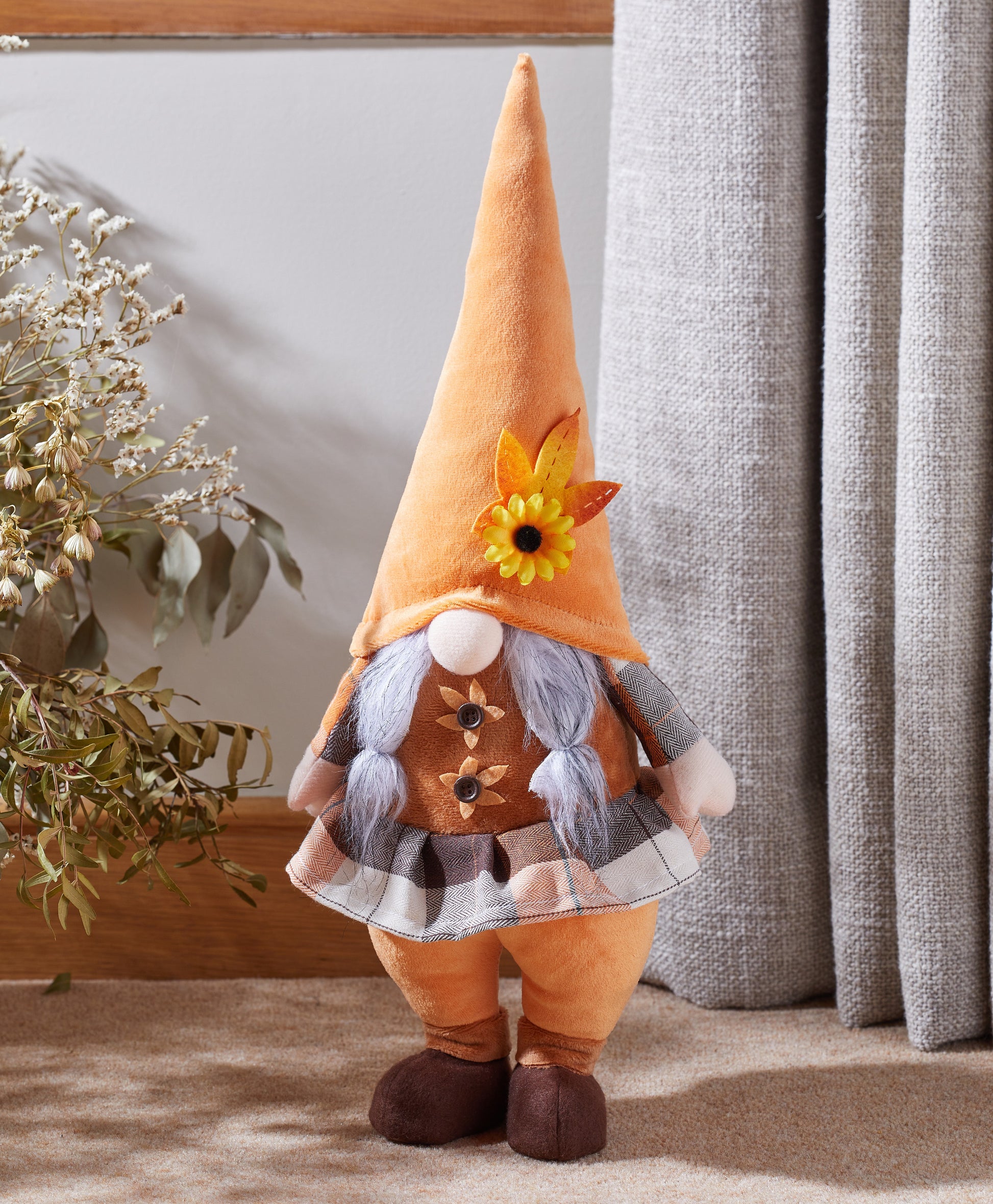 Decorative gnome with an orange hat and plaid outfit standing indoors.