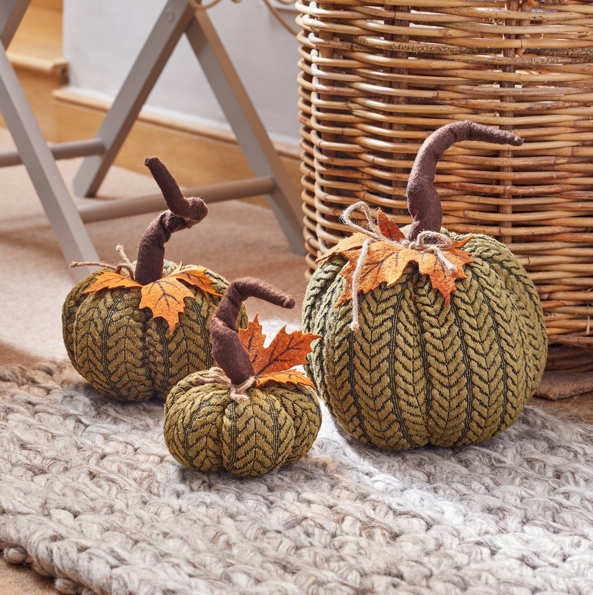 Knitted pumpkins with leaf decorations on a textured surface