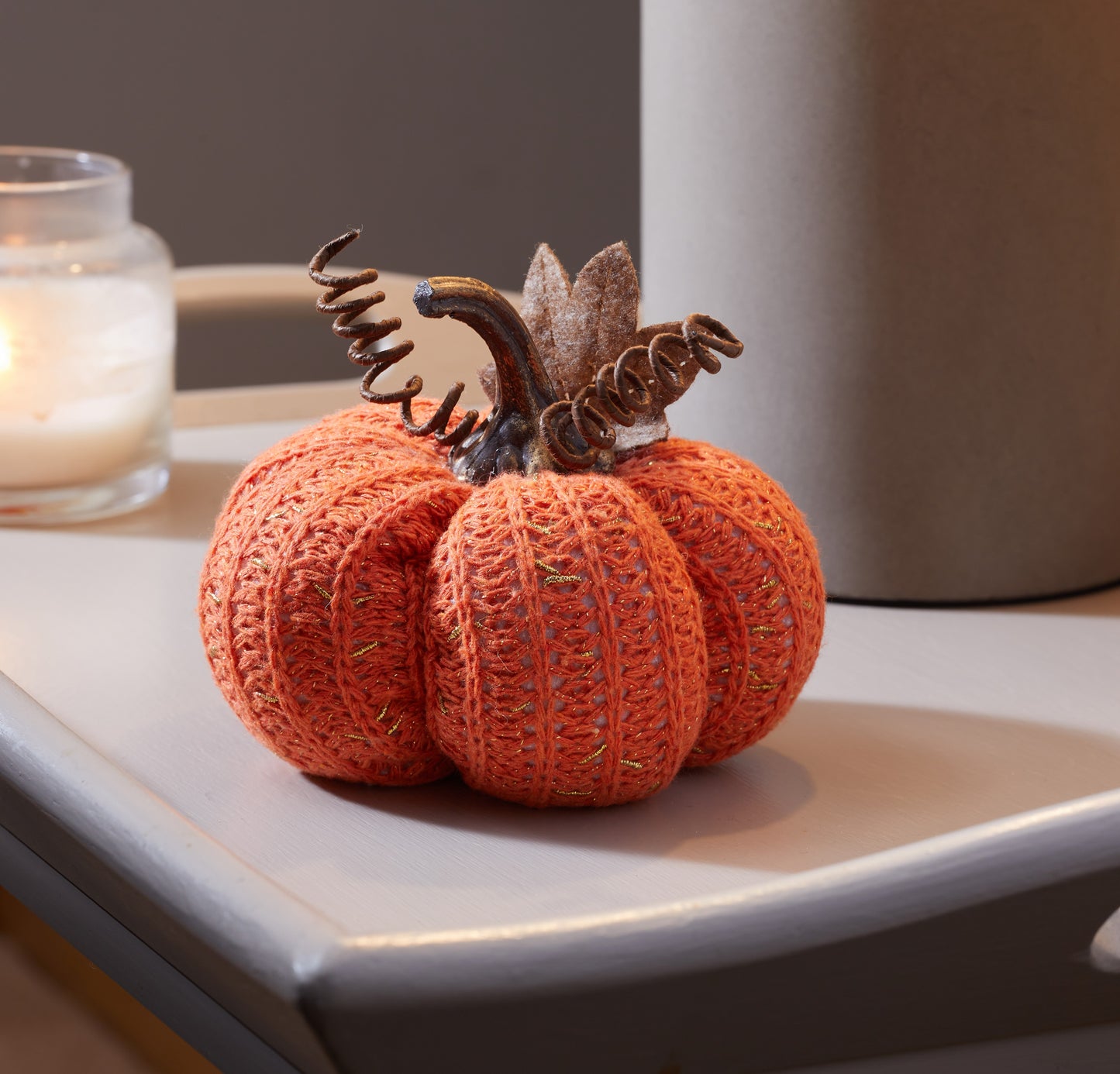 Knitted pumpkin decoration on a surface with a blurred background